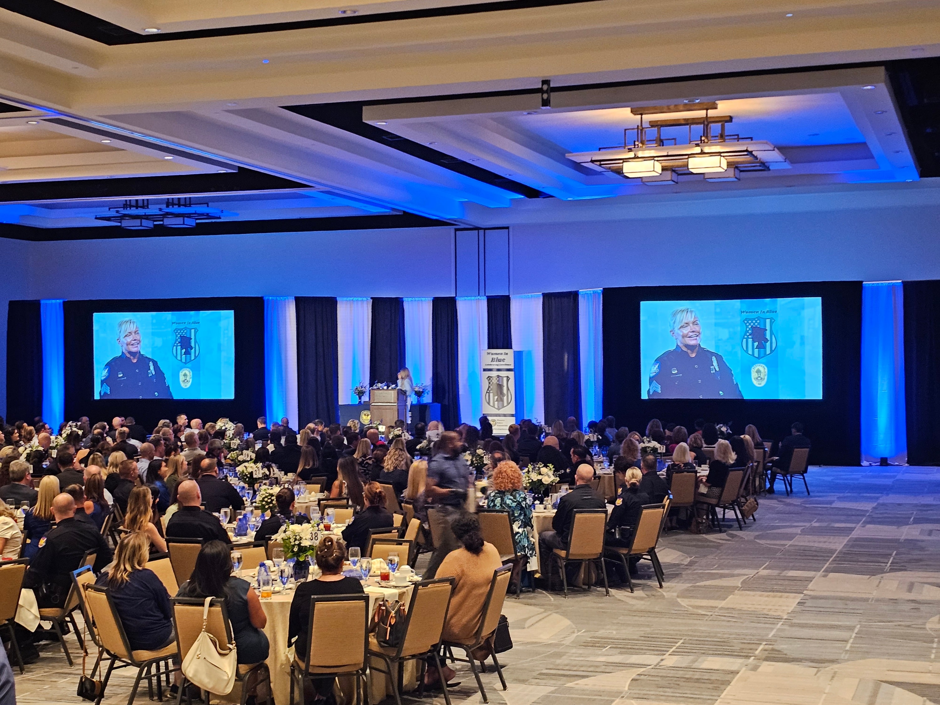 Large conference event with projection screens and blue uplighting