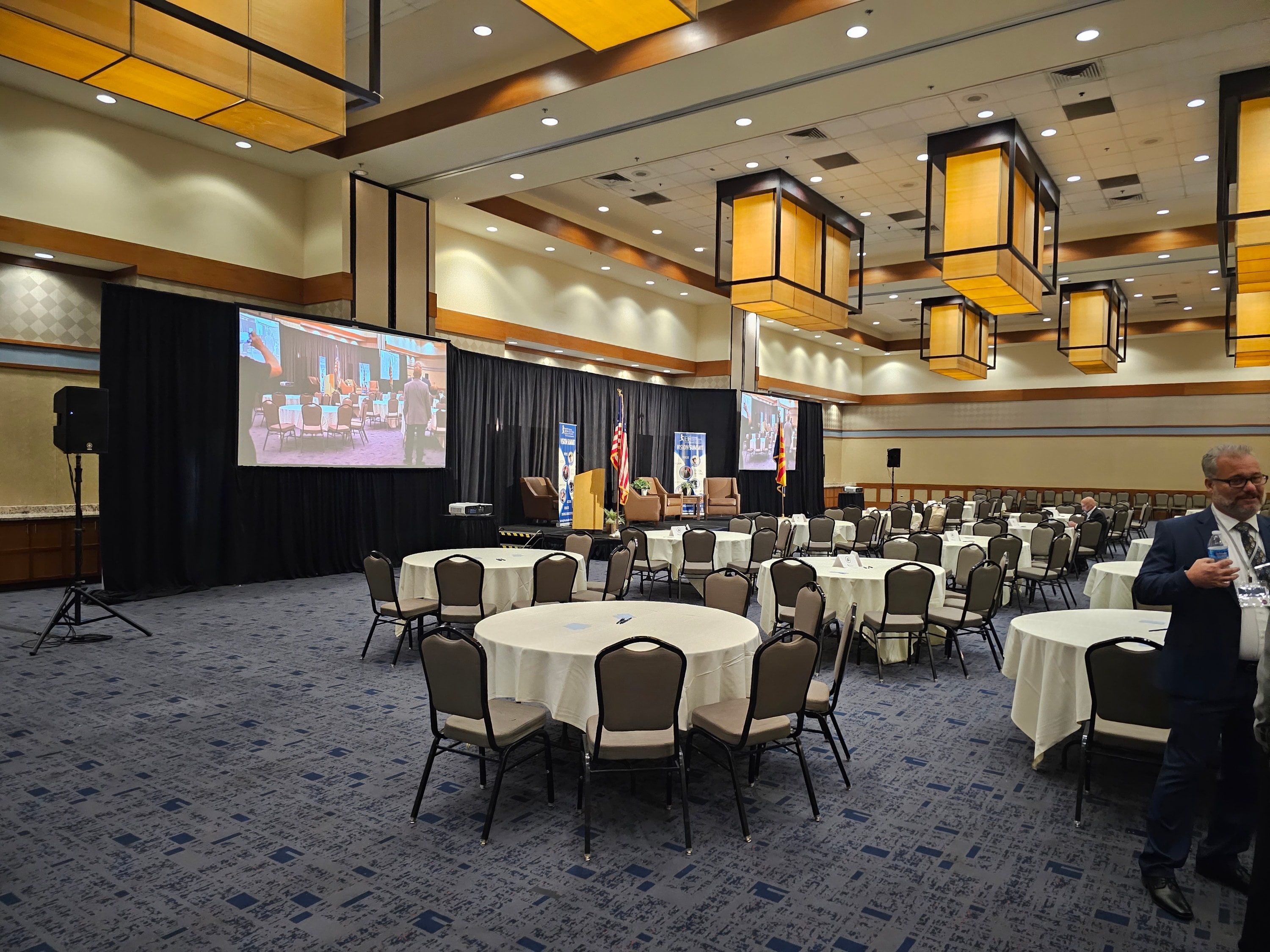 Conference ballroom with round tables and presentation screens