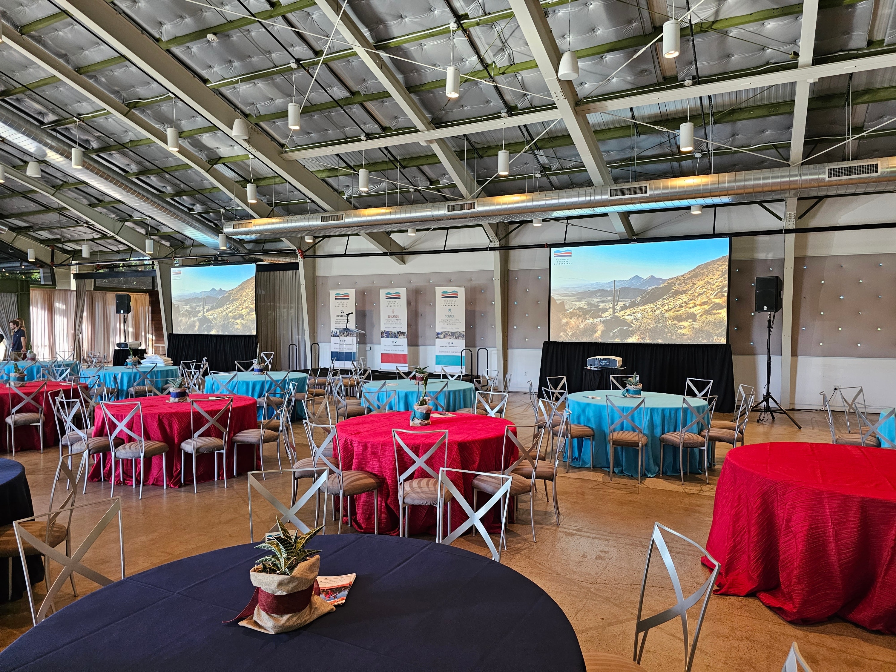 Event venue with red and blue tablecloths and dual screens
