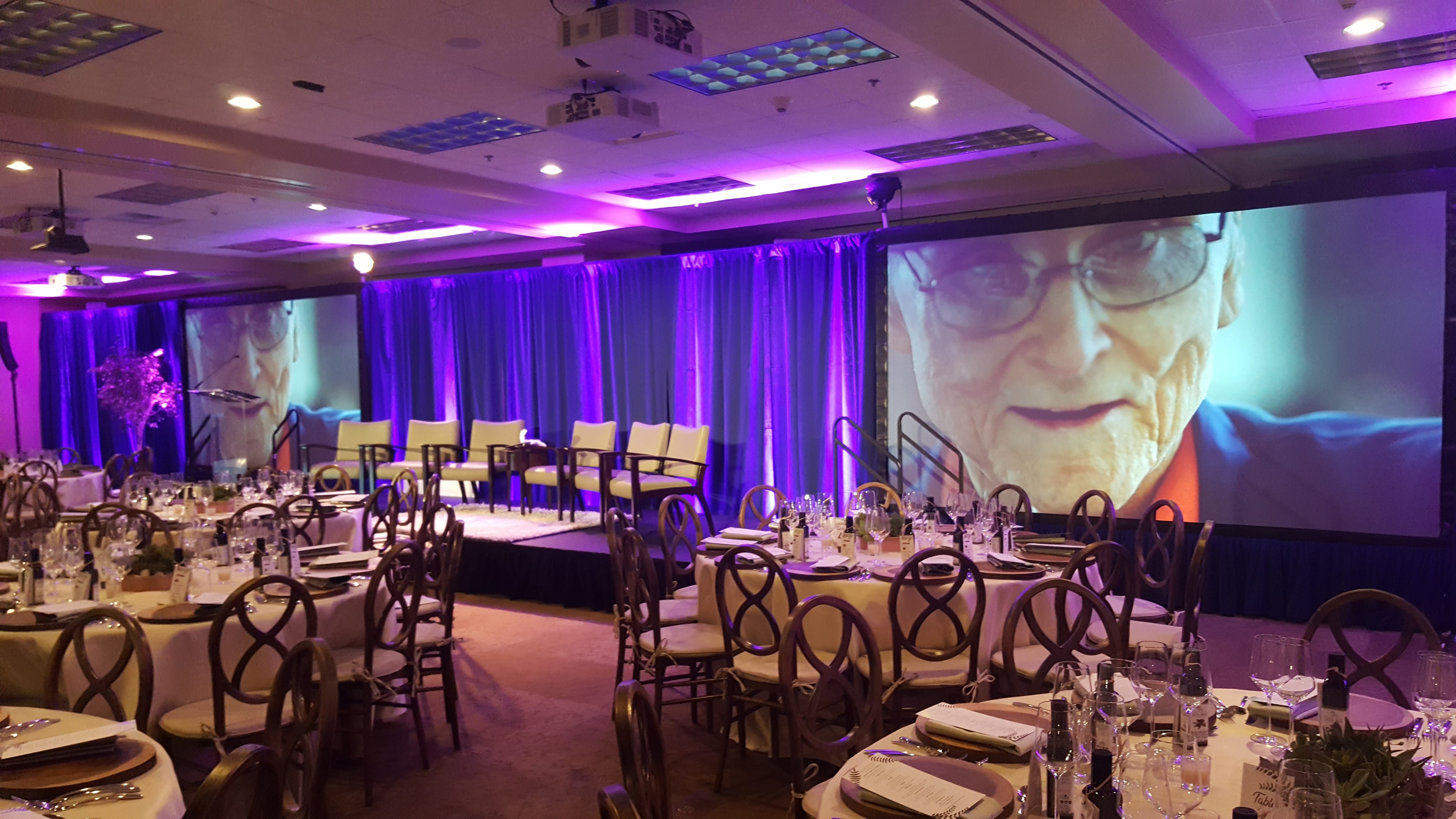 Elegant event venue with purple lighting and large projection screens