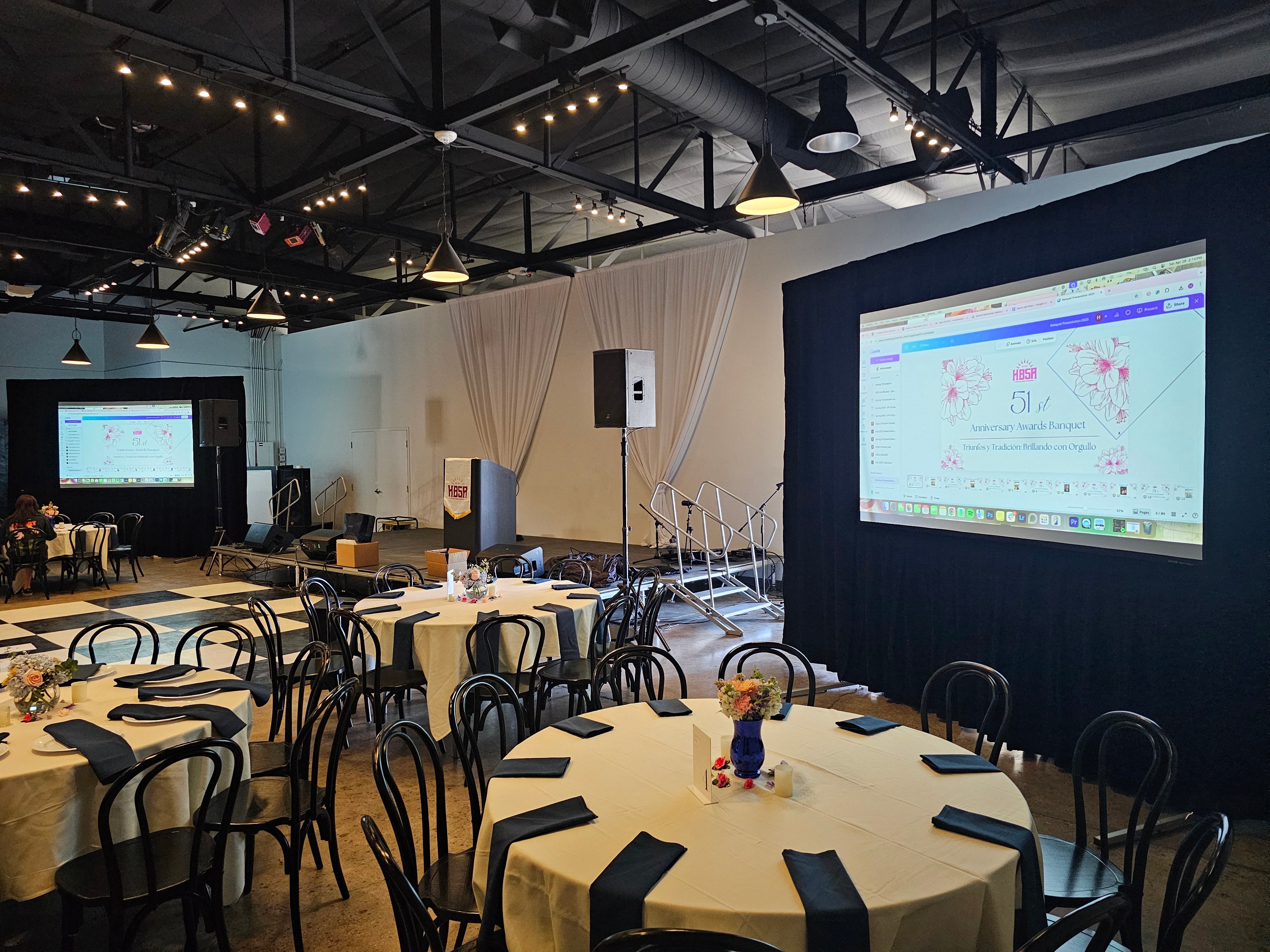 Banquet hall with rear projection screen and round tables set for event